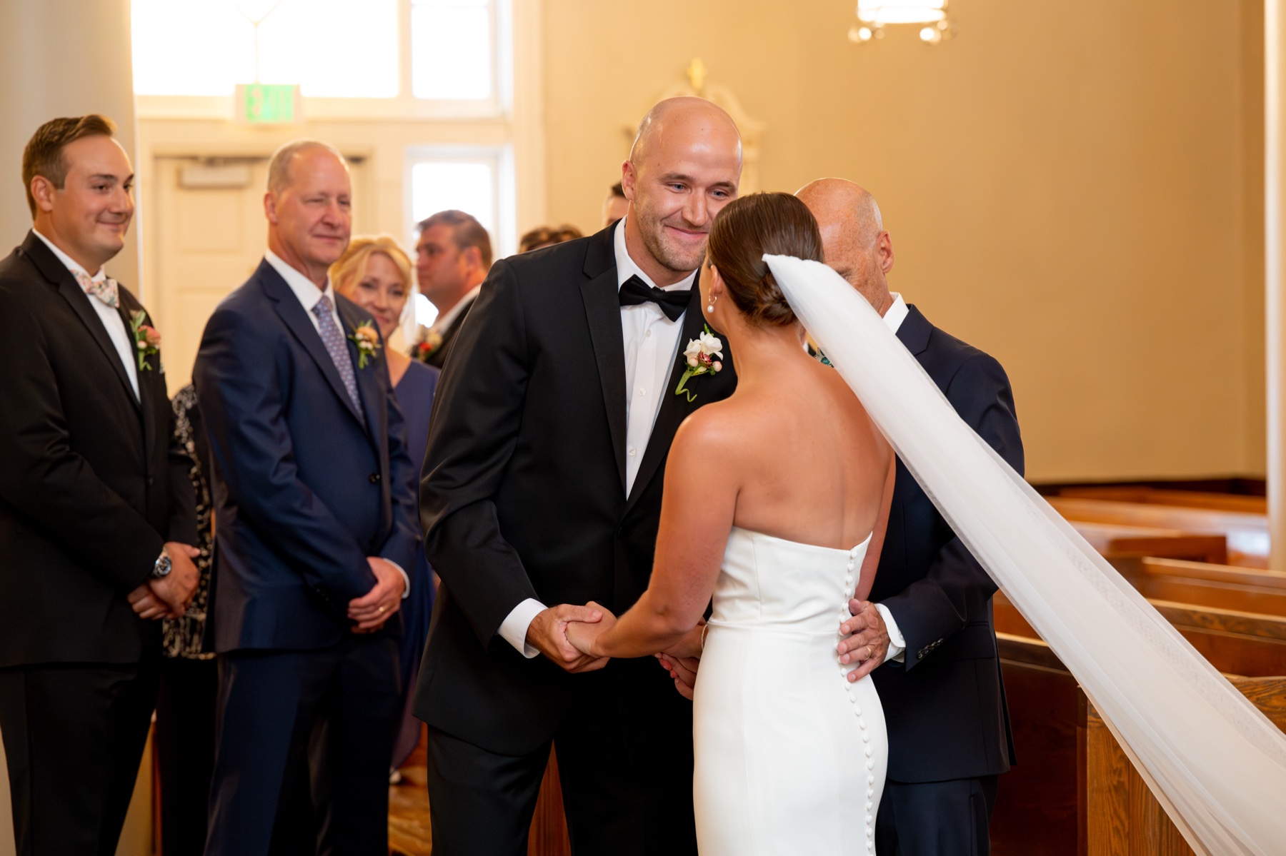 groom smiling as her takes the bride's hand from her father's during the wedding ceremony 