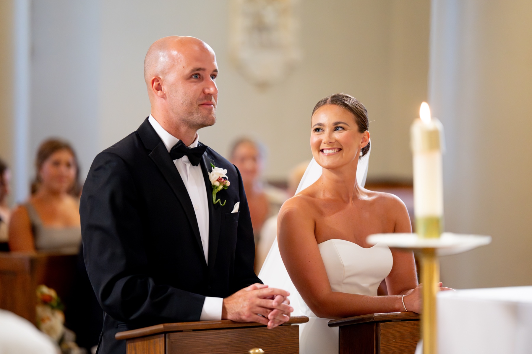 bride smiling at the groom as they kneel at the altar for the wedding ceremony at their South Shore Summer Wedding