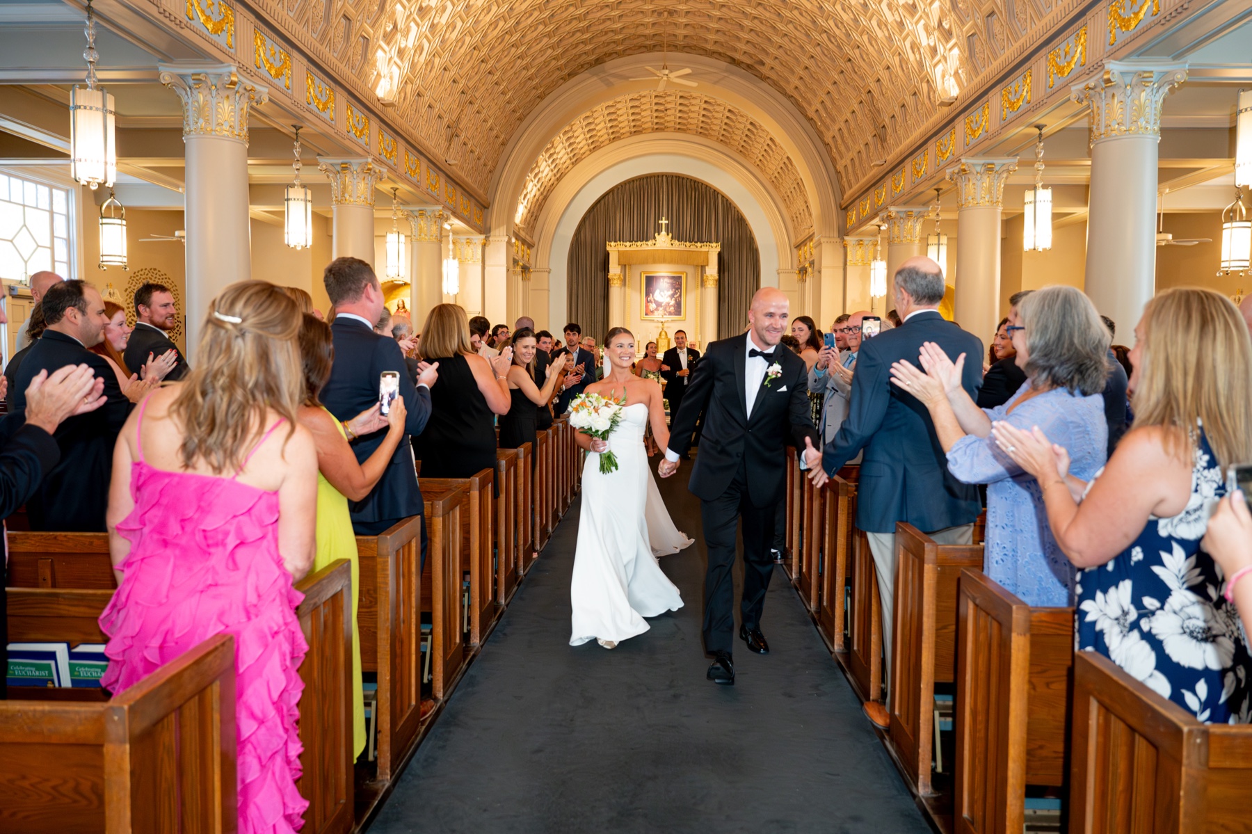 groom shaking hands with wedding guests as he and the bride walk back up the church aisle after the wedding ceremony