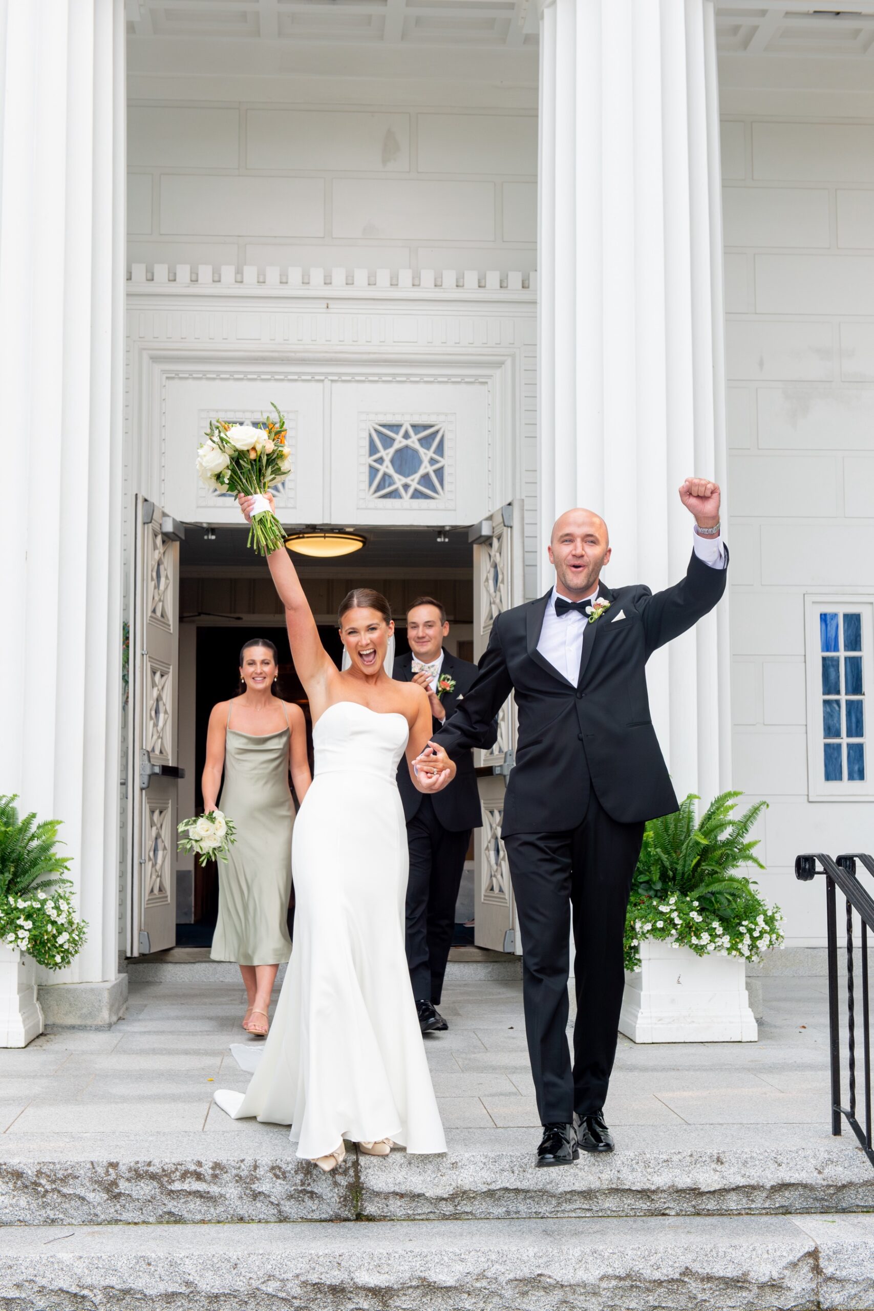 bride and groom raising hands in celebration outside of the church after their Elegant South Shore Summer Wedding ceremony 