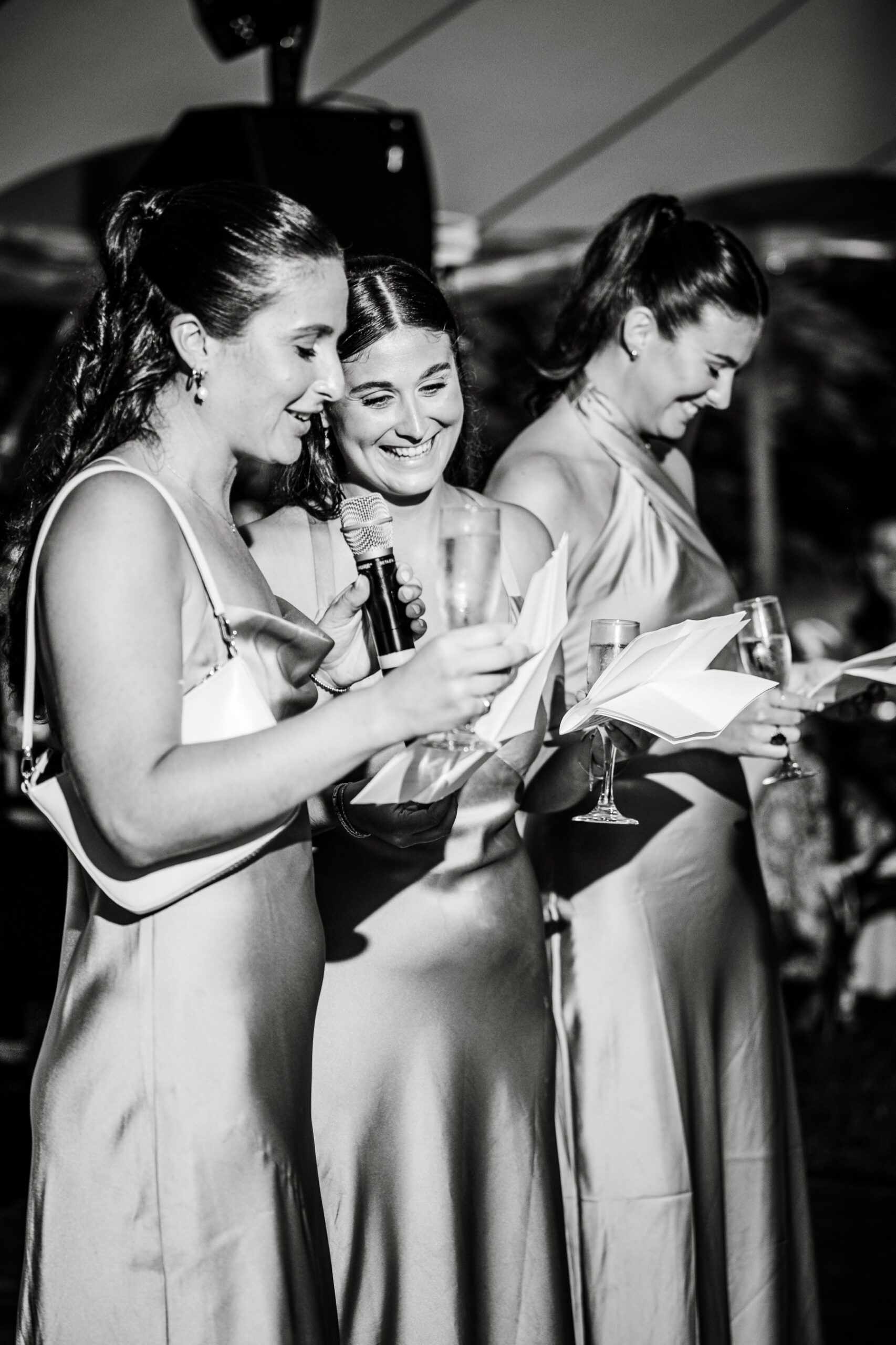 three bridesmaids stand at the microphone giving their wedding toast 