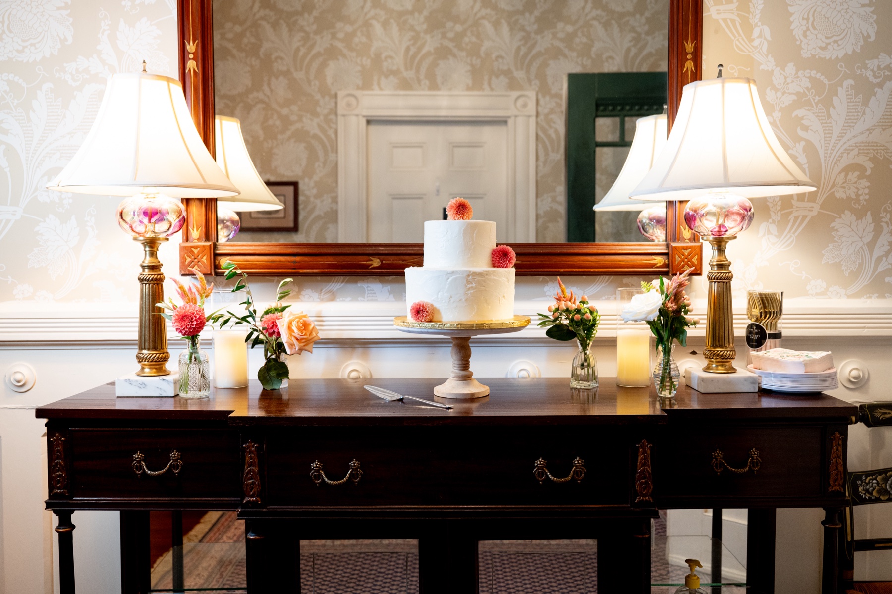 antique table decorated with pink and orange flowers and the white wedding cake