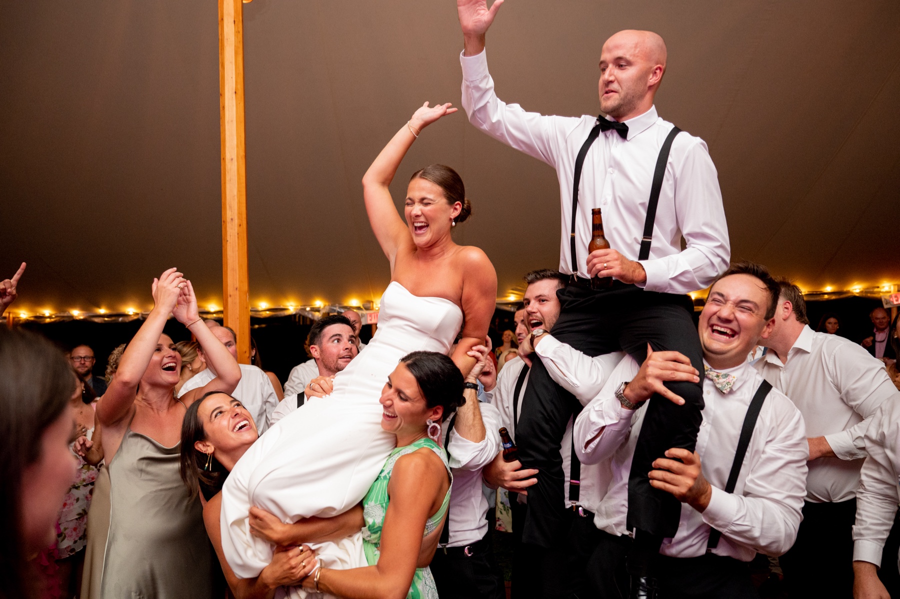 guests lift the bride and groom up in the air on the South Shore Summer Wedding dance floor 