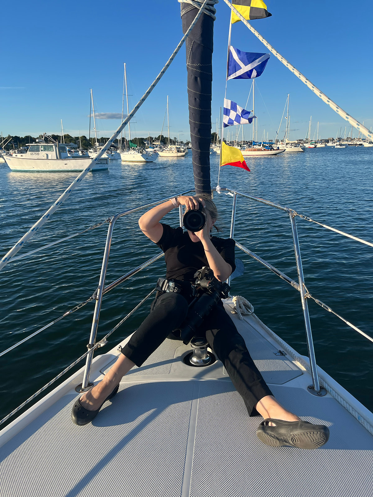 wedding photographer wearing black crocs while photographing a session on a boat