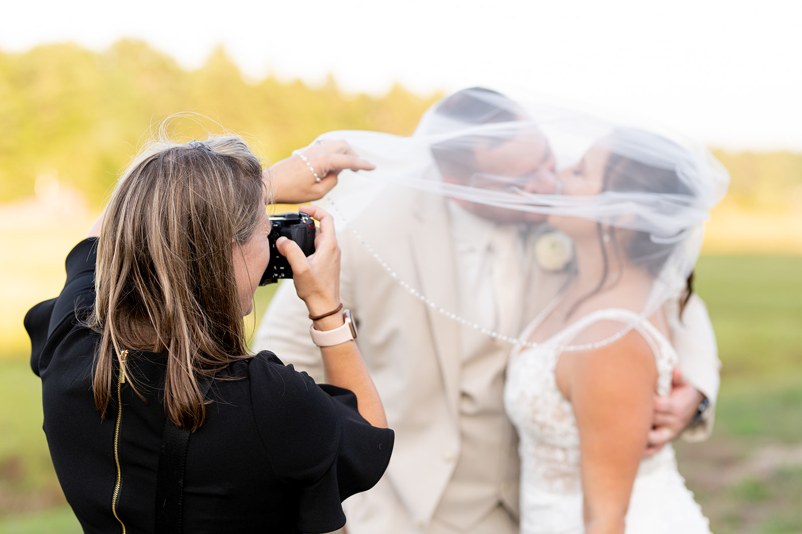 a wedding photographer capturing a kiss of her clients under the bride's veil