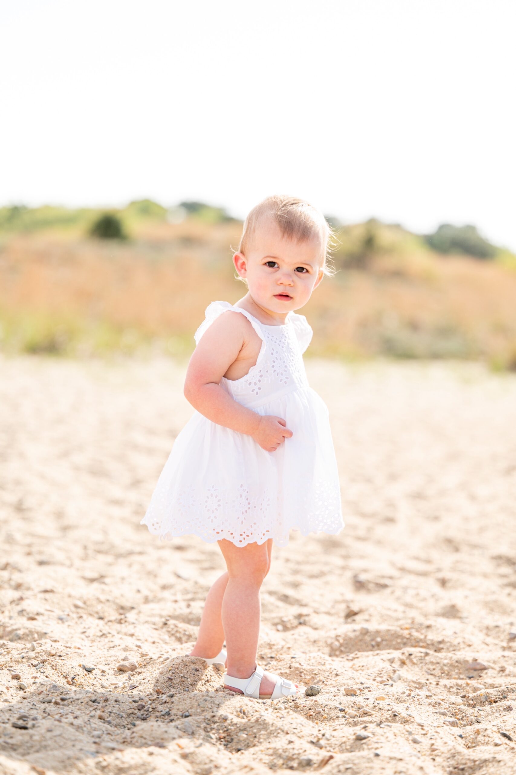baby girl in white lace dress on the beach of cape cod