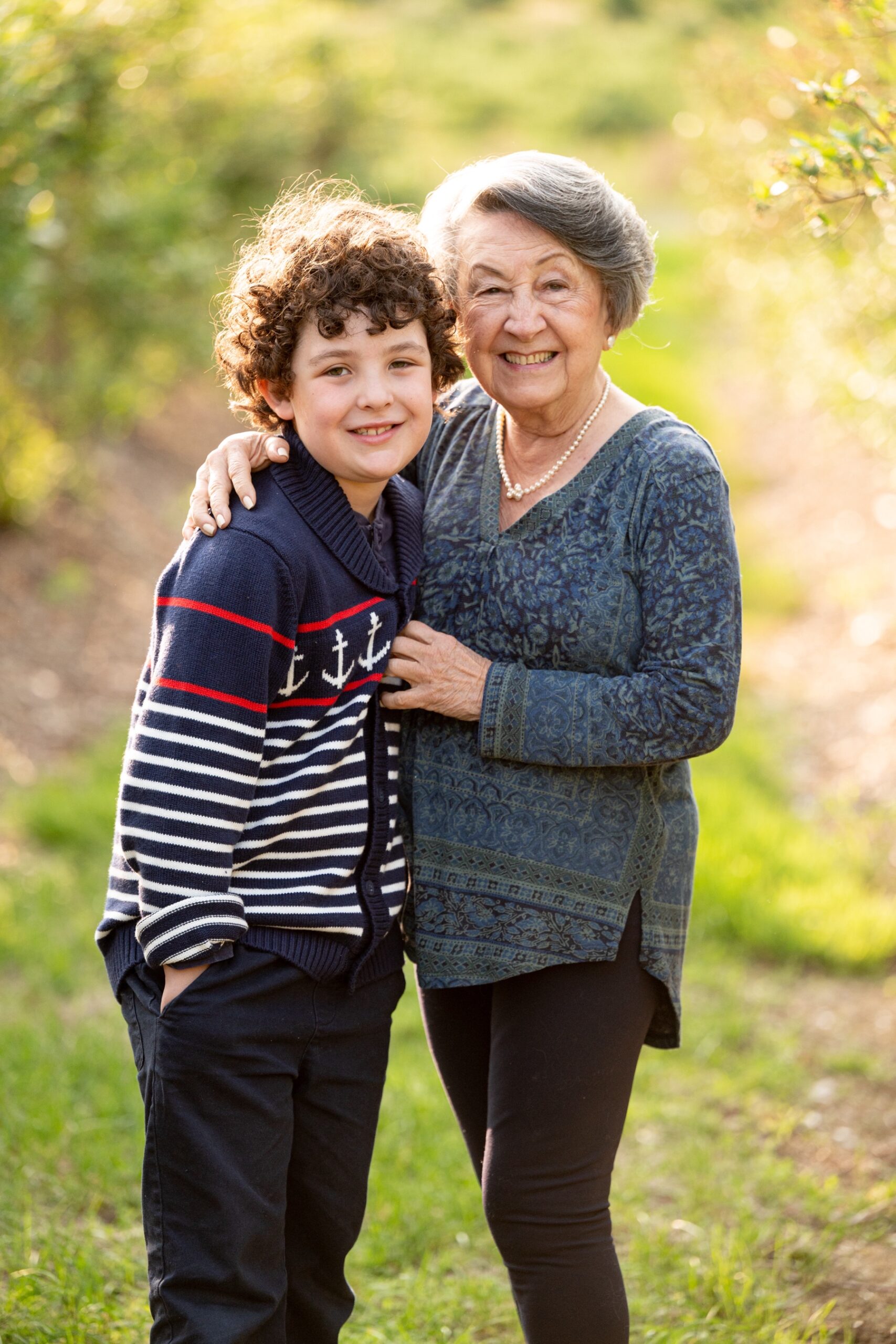 boy wearing blue and white striped sweater standing with his grandmother for family photos 