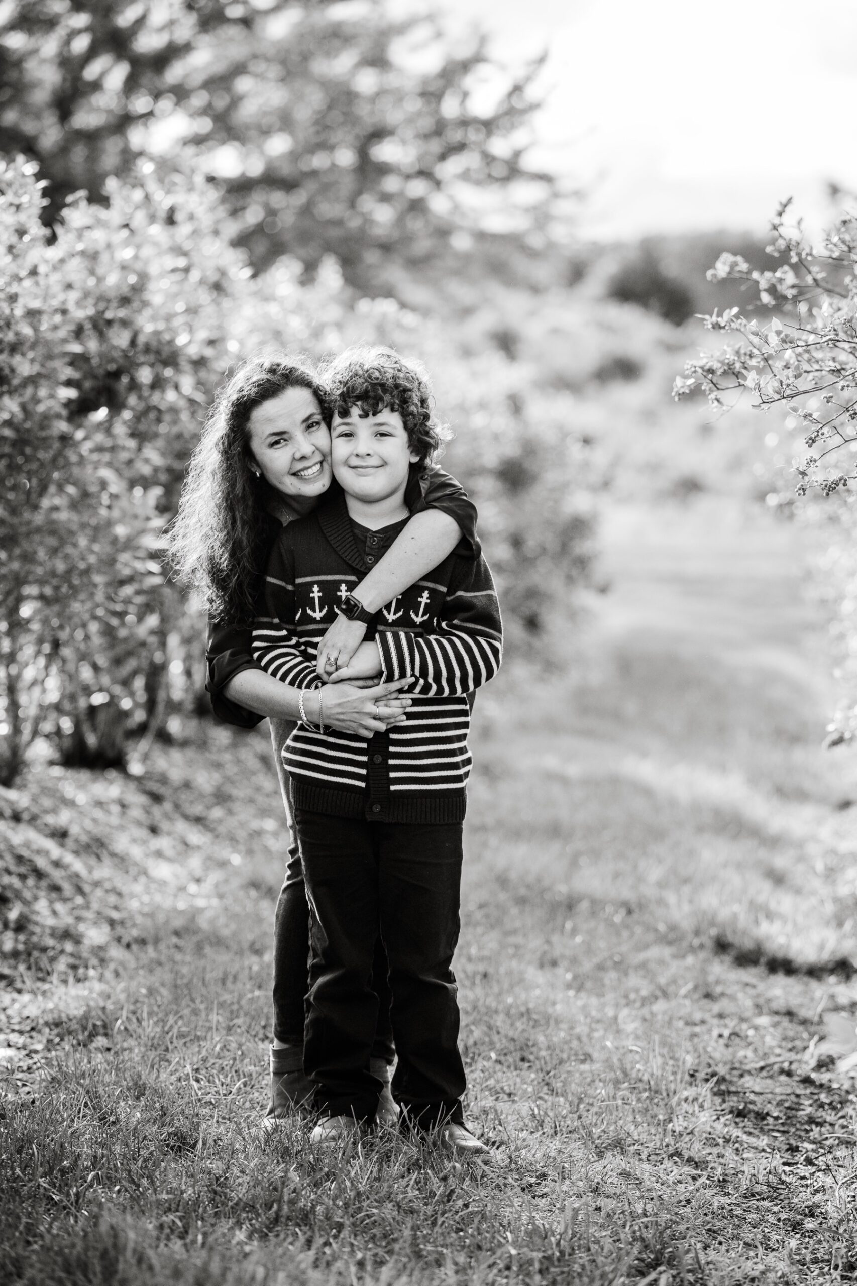 mother hugging her son in apple orchard for spring family portraits