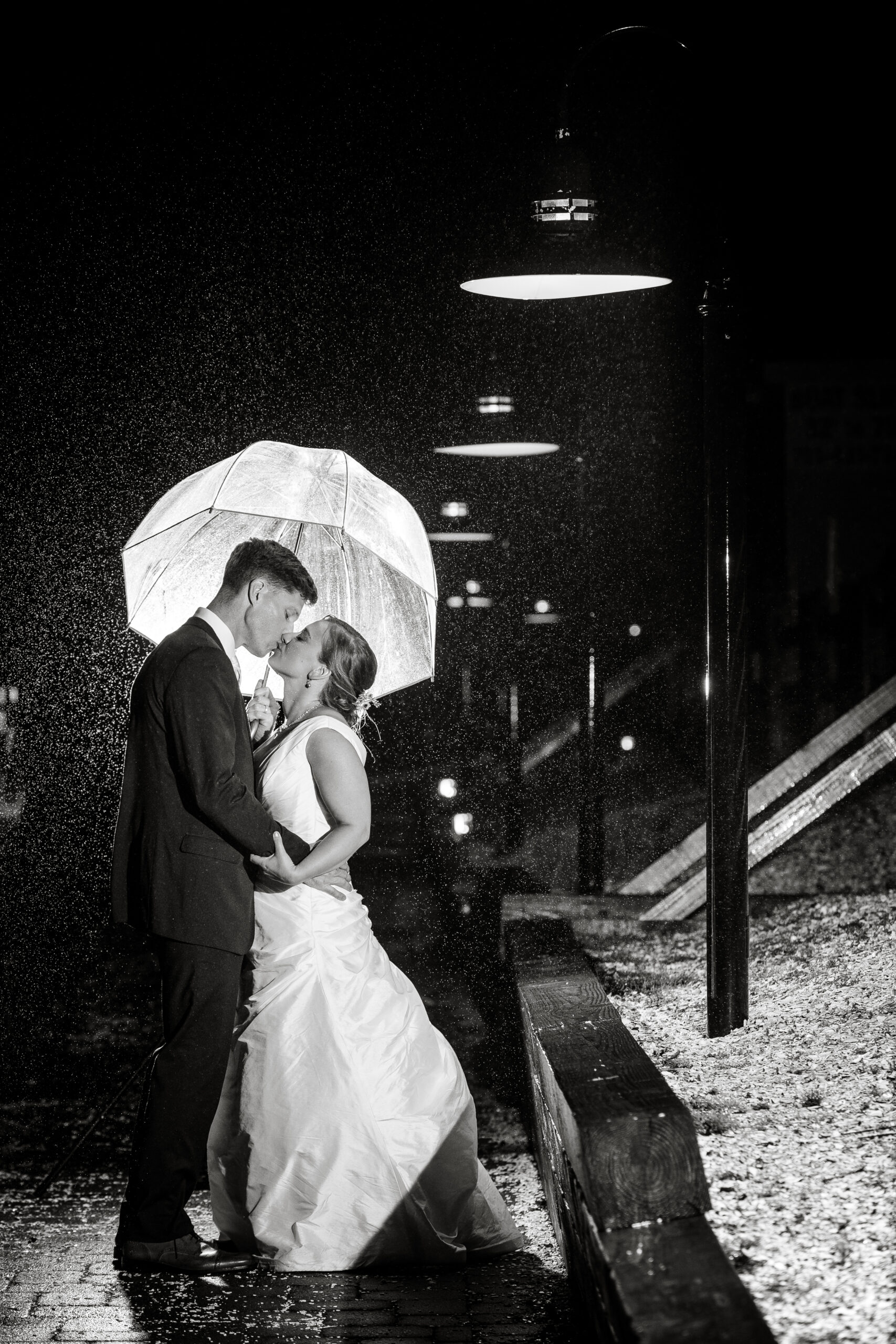 bride and groom kissing under an umbrella at night at the Rainy Day Wedding
