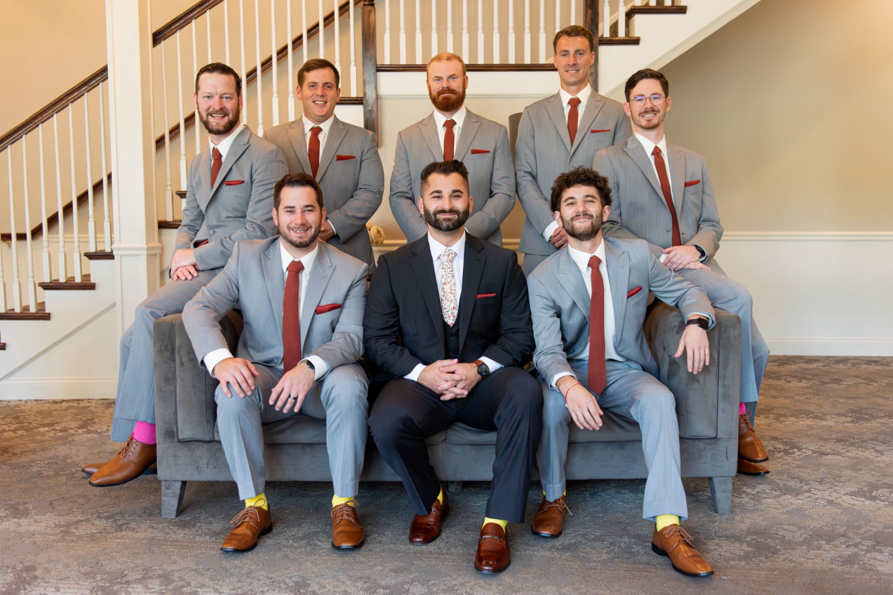 groomsmen sitting in grey suit with red ties 