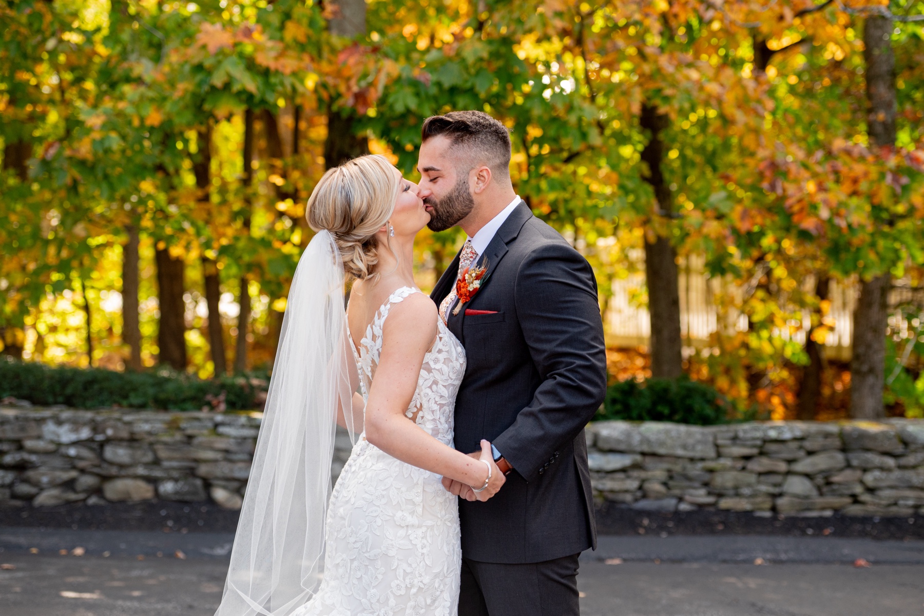 bride and groom kissing in front of fall foliage 