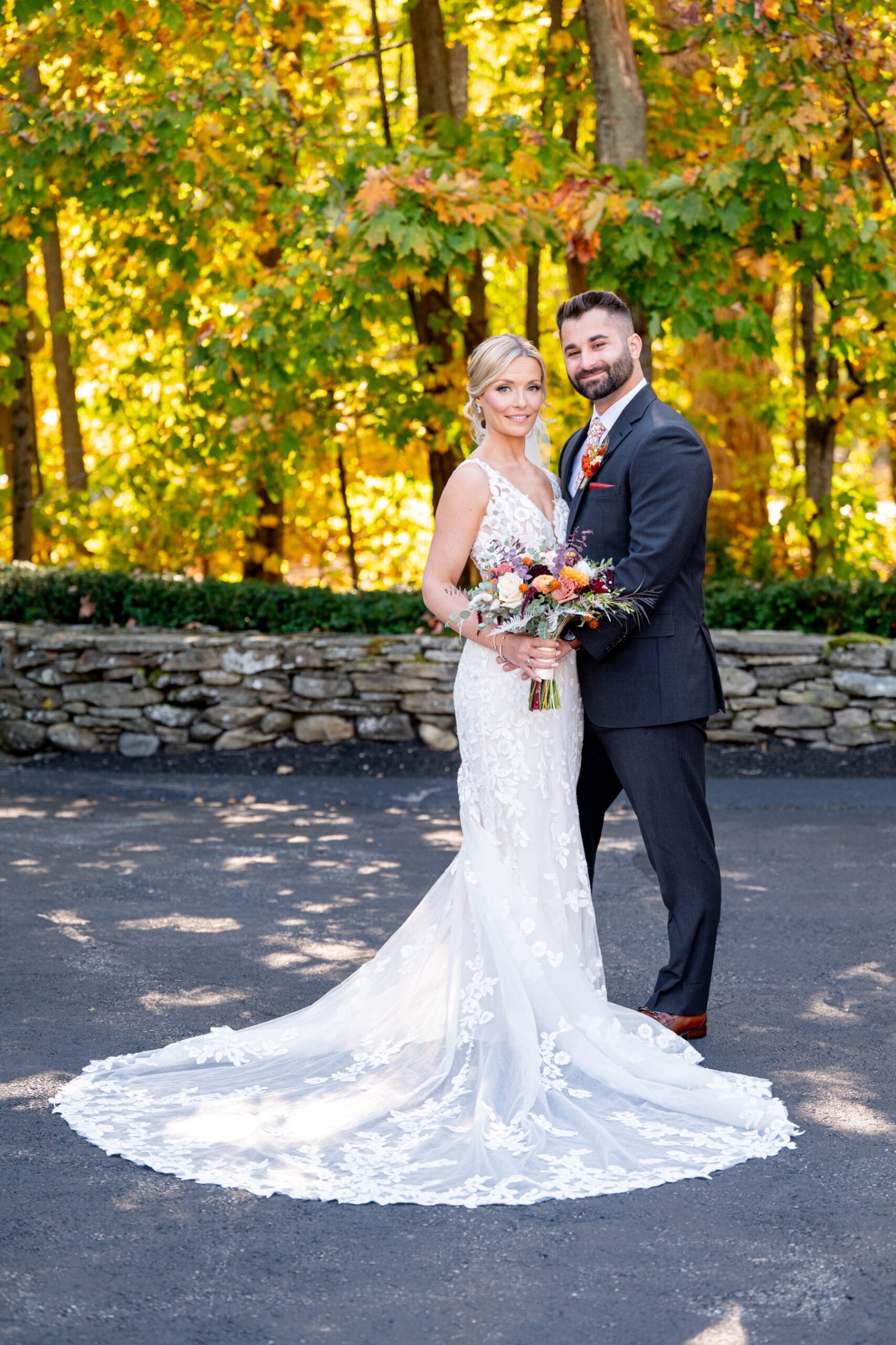 bride and groom standing in front of fall foliage at the chocksett inn
