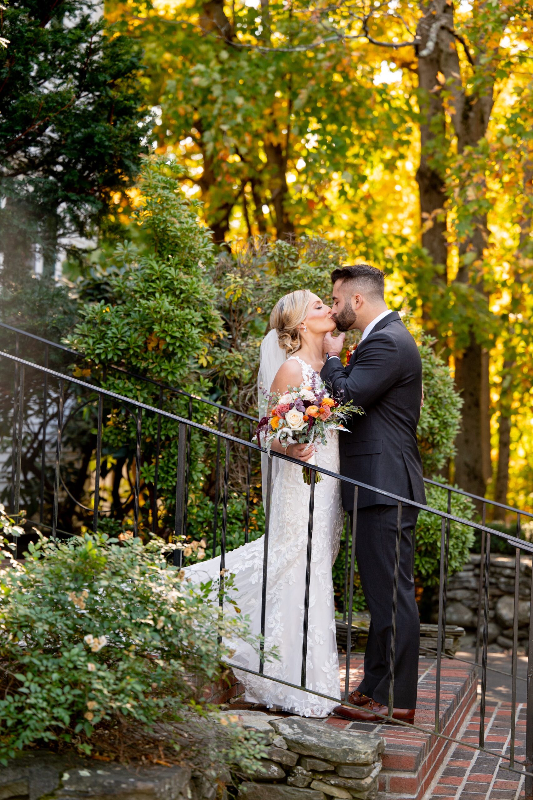 bride and groom kissing in front of fall foliage at the chocksett inn