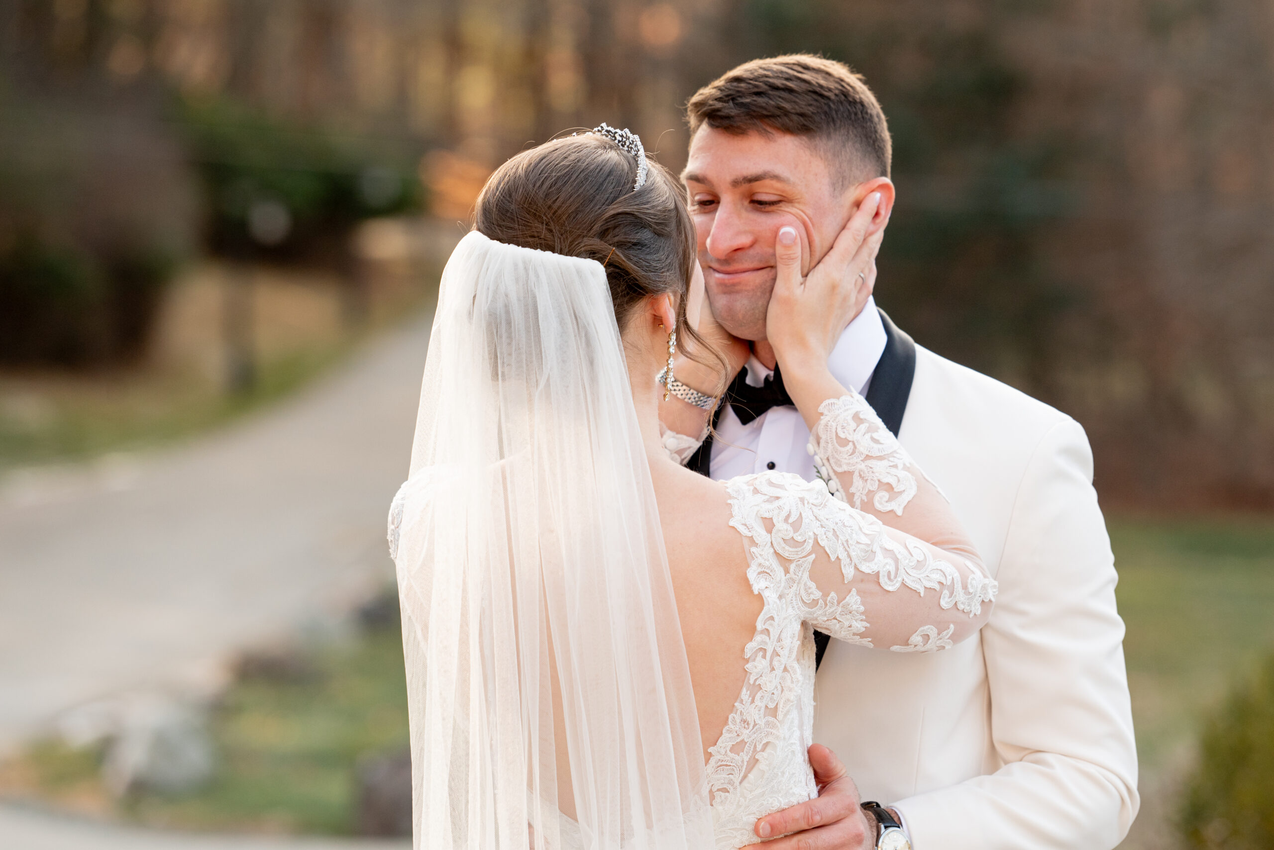 bride holding her groom's face as her looks at her in her wedding dress after the first look 