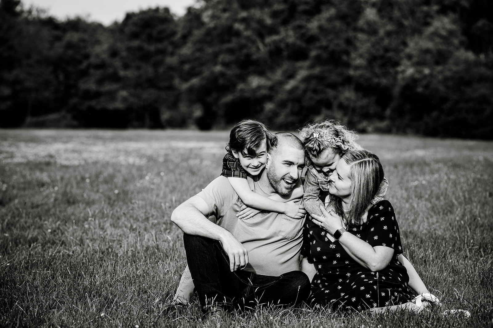 parents sitting on the ground with kids running up and hugging them
