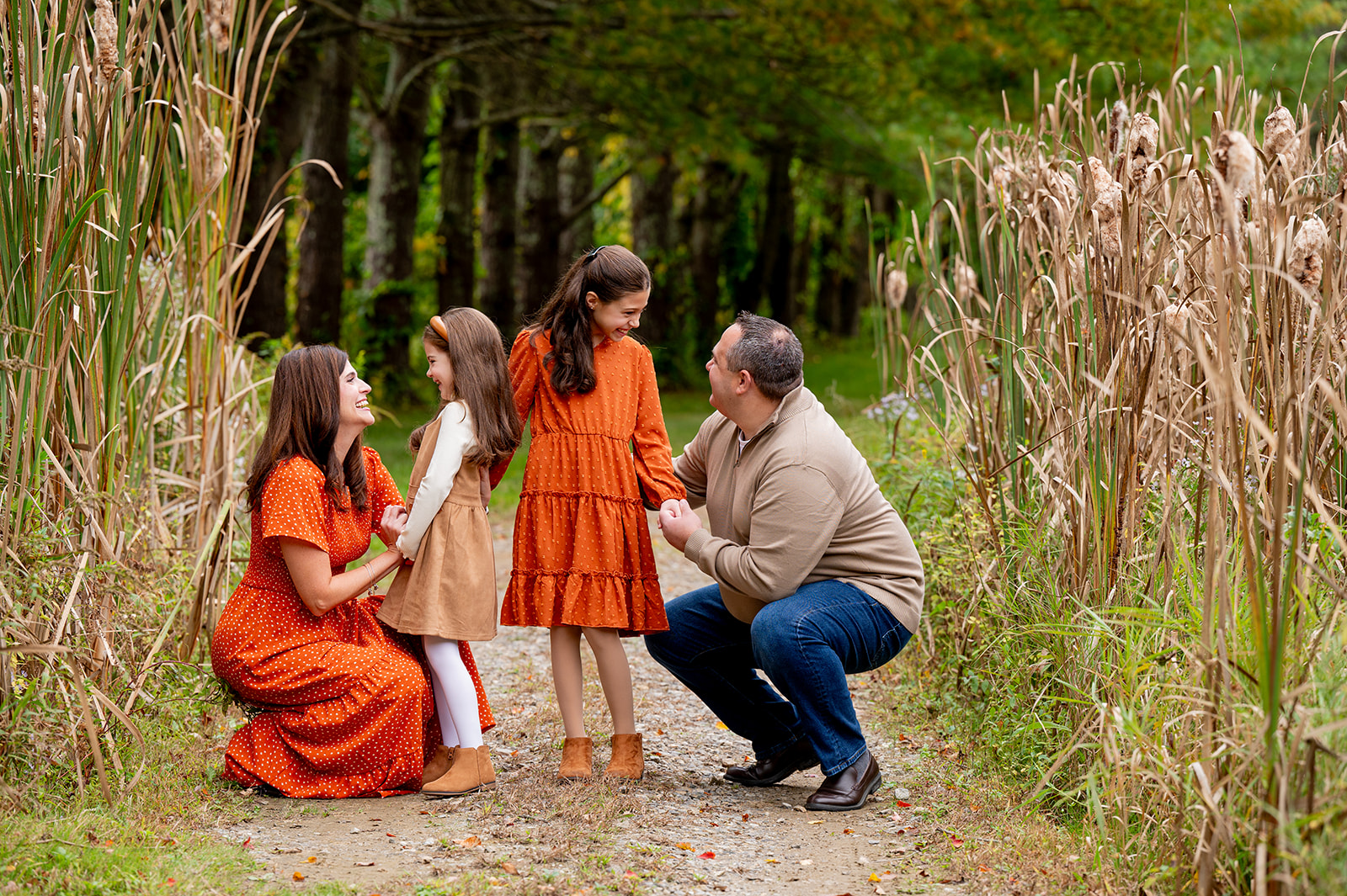 parents squatting down to eye level with their two daughters in a field