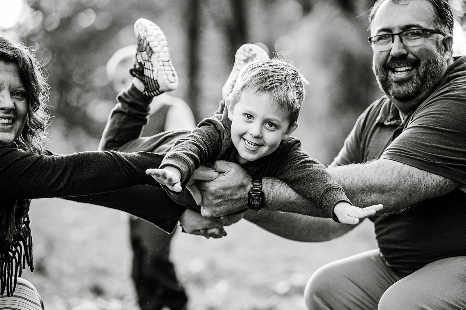 parents holding little boy up with their arm outstretched like superman