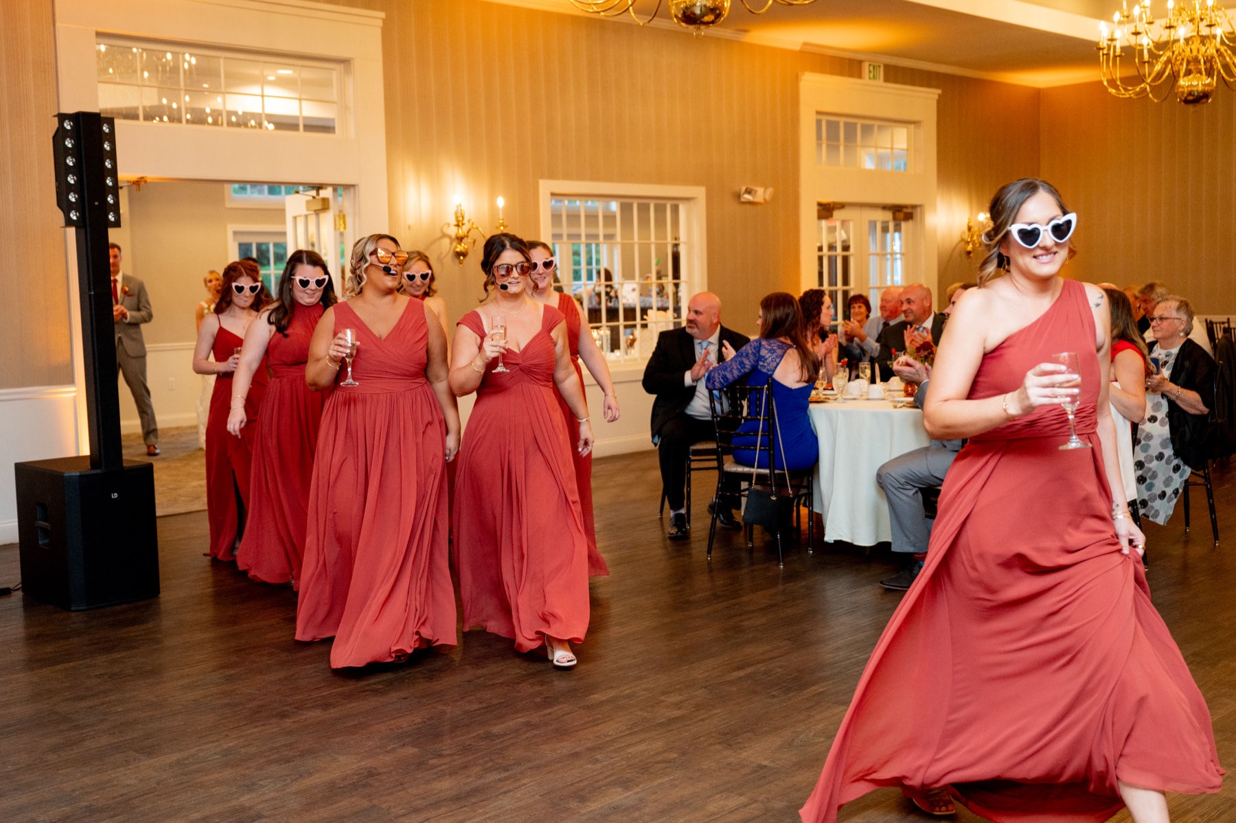 bridesmaids wearing red dresses and heart-shaped sunglasses entering the reception area 