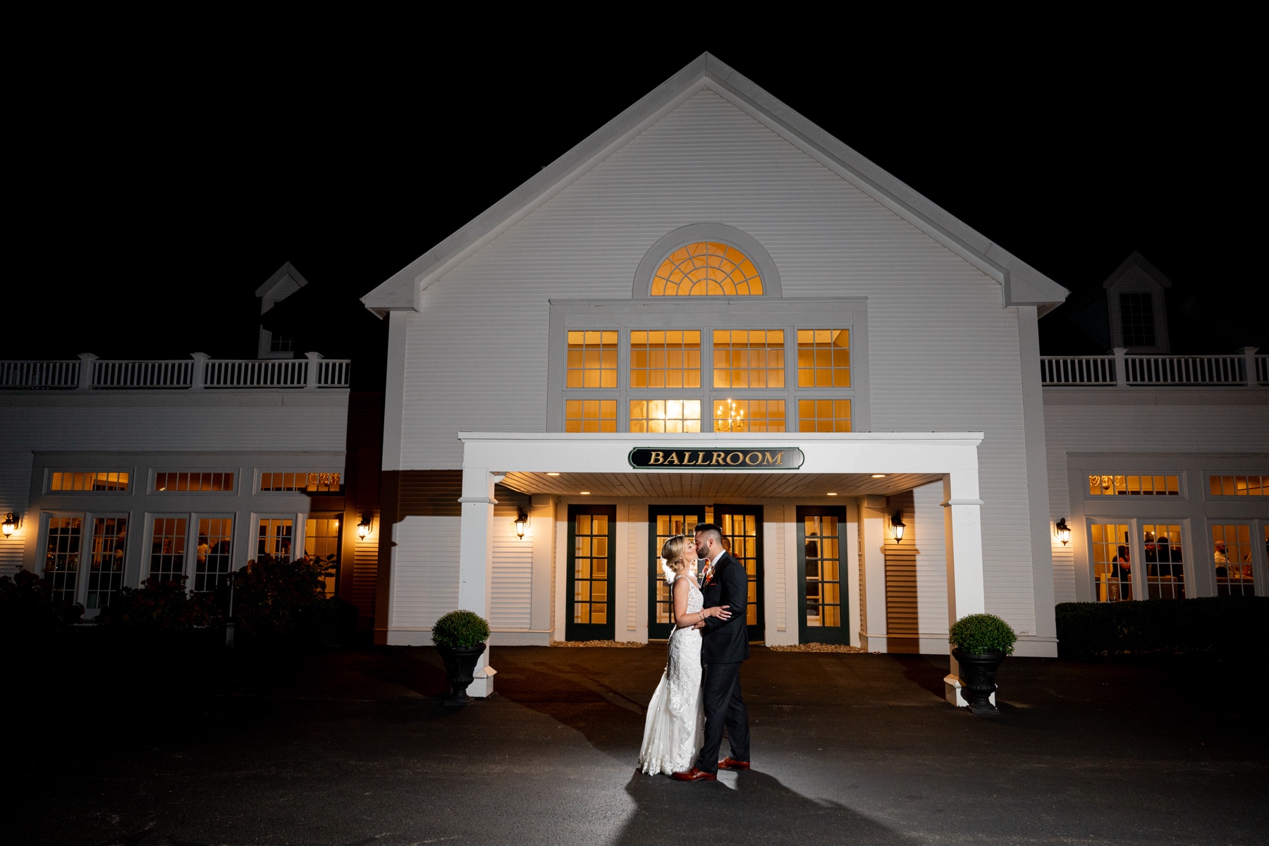 bride and groom kissing in front of the entrance to the ballroom of chocksett inn 