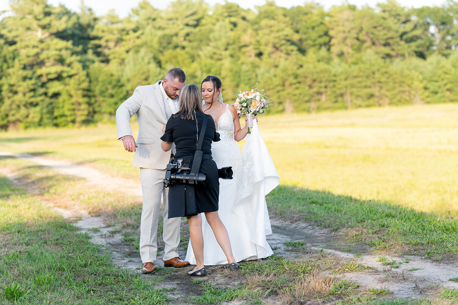 wedding photographer wearing black dress while helping the bride and groom with their clothes