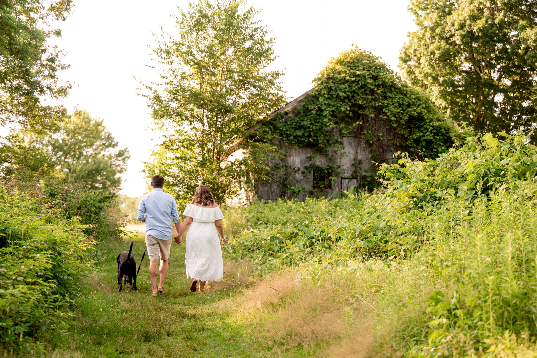 couple walking their dog along Shaw Farm for an engagement session