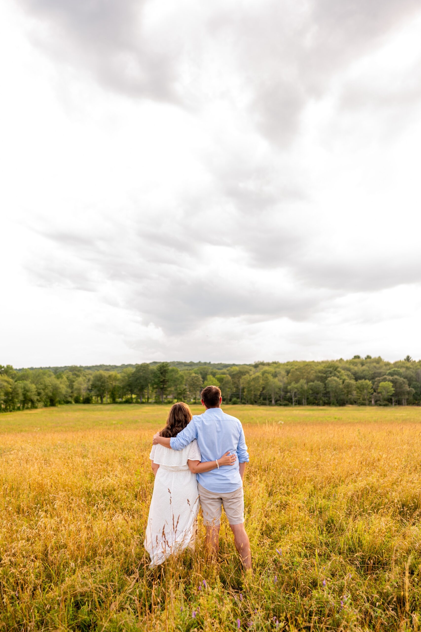 couple standing in the middle of a yellow field at Shaw Farm for an engagement session