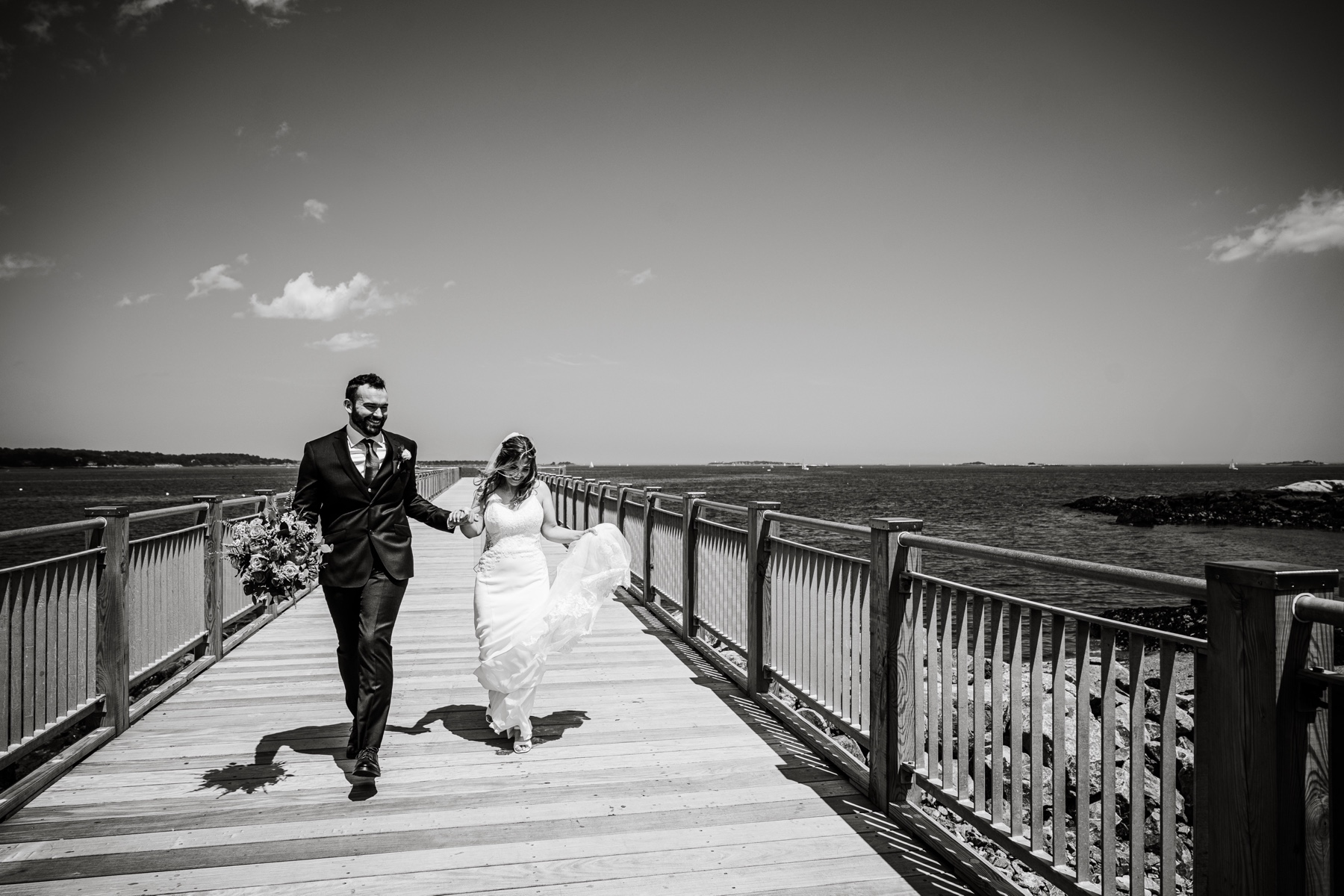 bride and groom walking down the pier holding hands