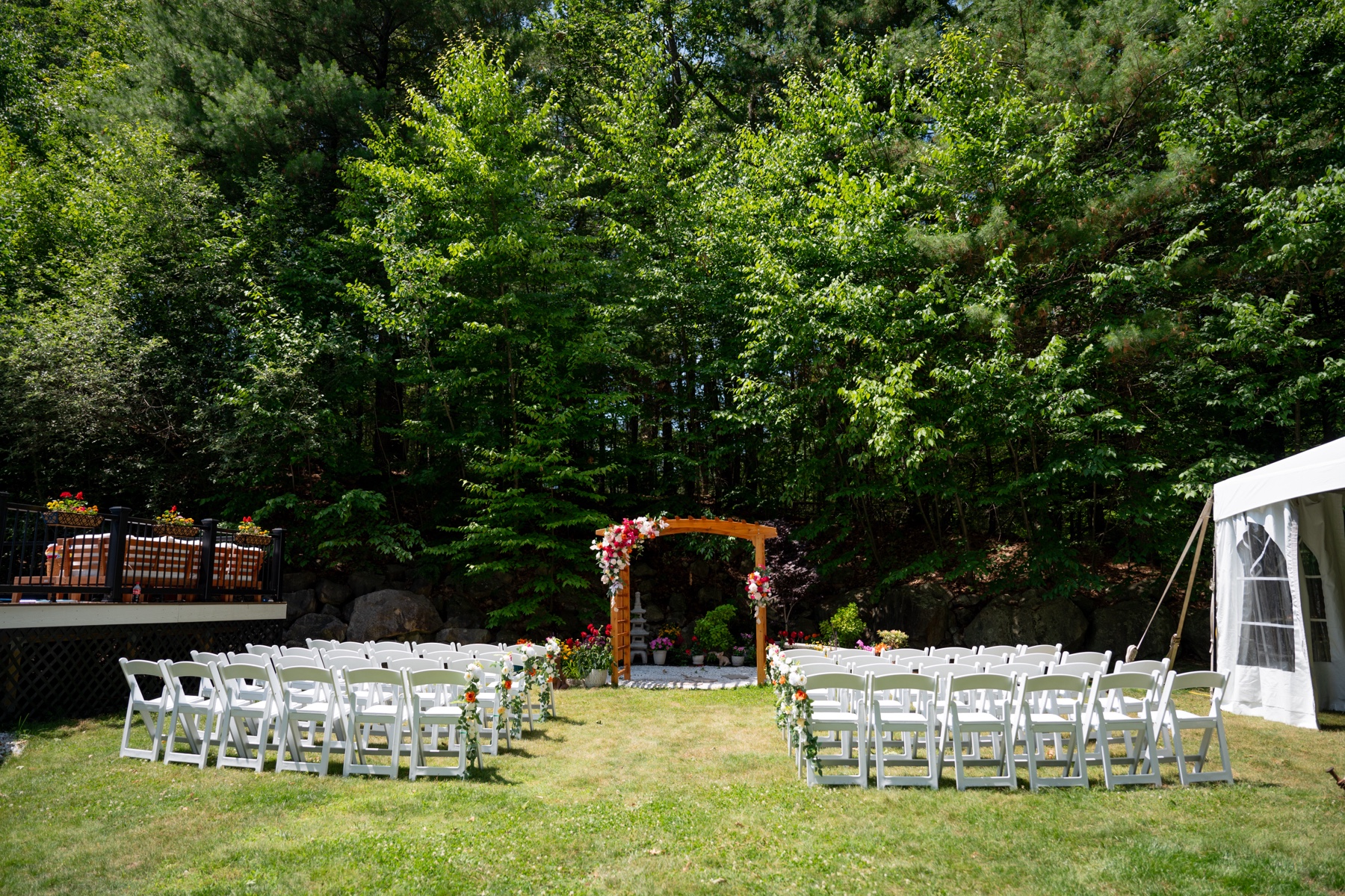 a wedding ceremony set up in the backyard with greenery