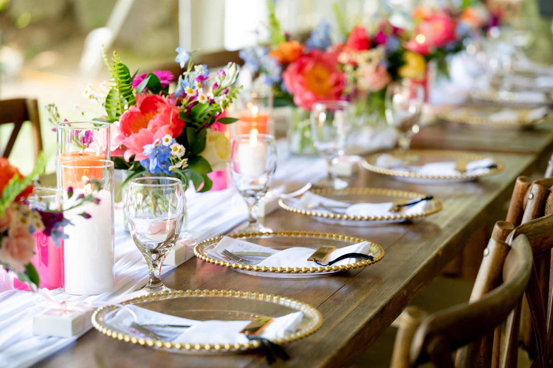 backyard wedding reception with wood tables and bright floral centerpieces 