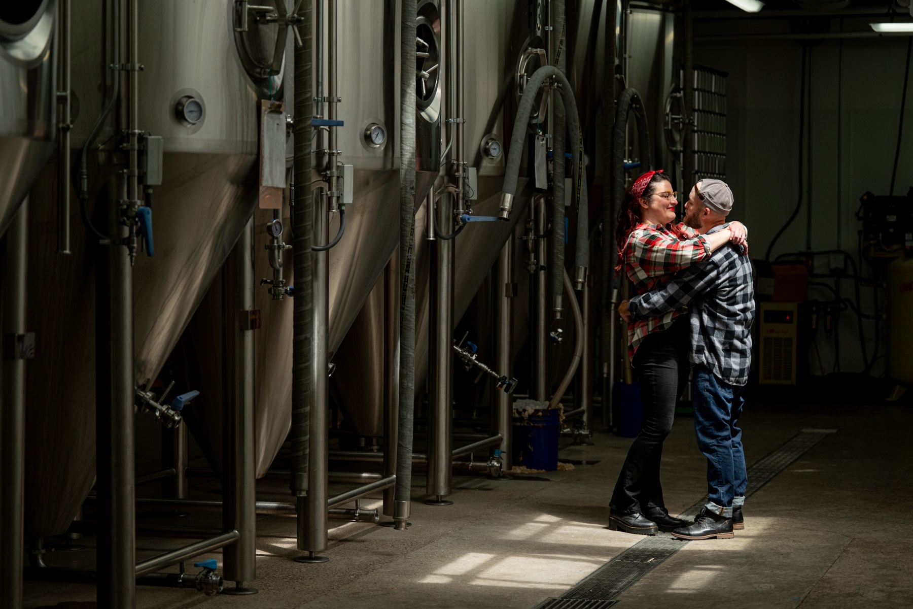 couple hugging in front of beer brewing tanks