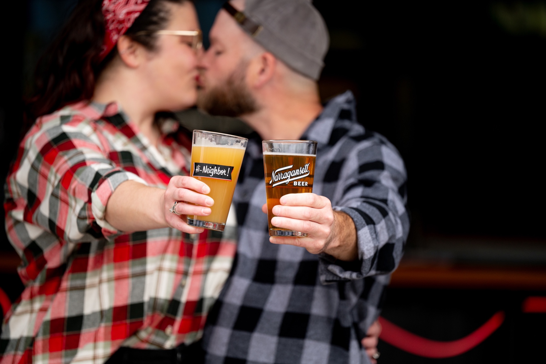 couple kissing in background while holding out their beers