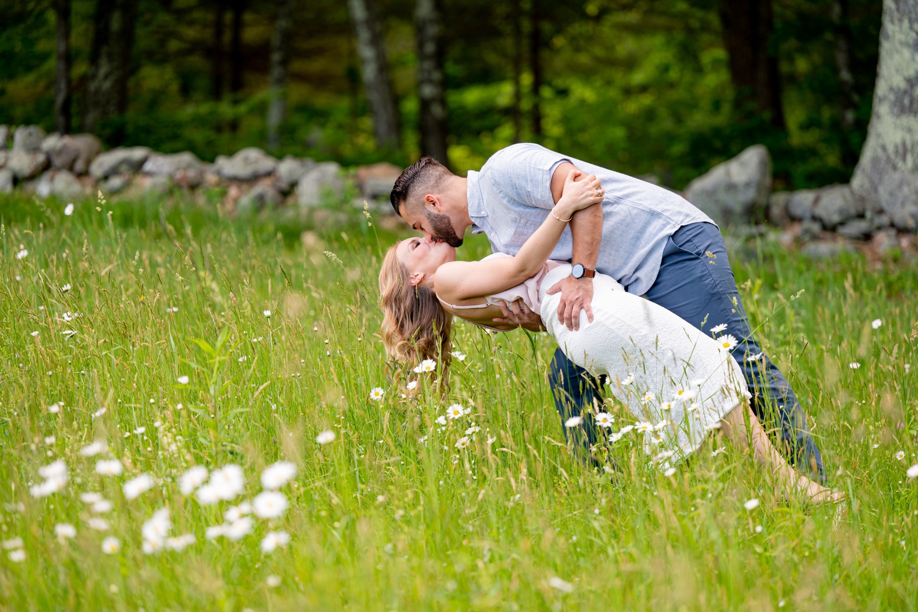 couple kissing in a green grassy field with white flowers