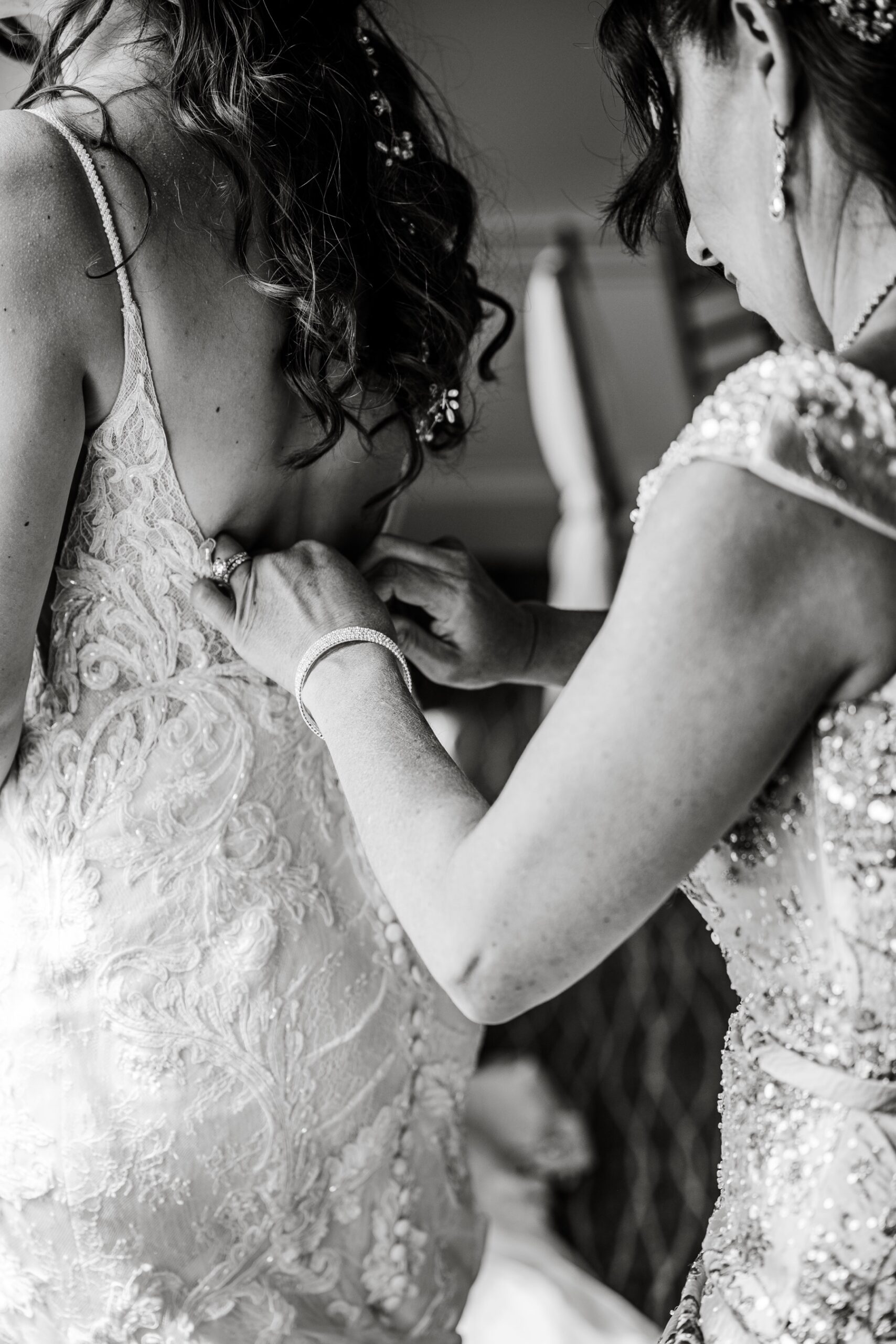 mother of bride zipping up bride's wedding dress