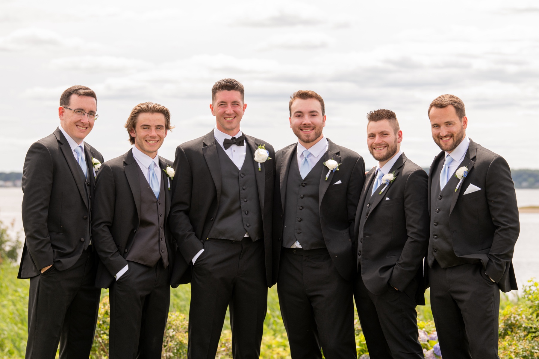 groom standing with his groomsmen in Warwick RI before wedding ceremony in black tuxes