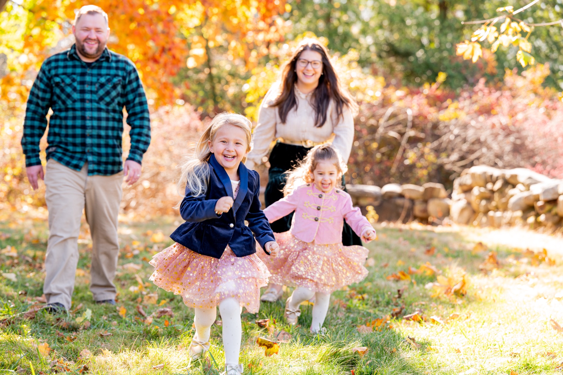 two young girls wearing pink tutus running through a field with parents