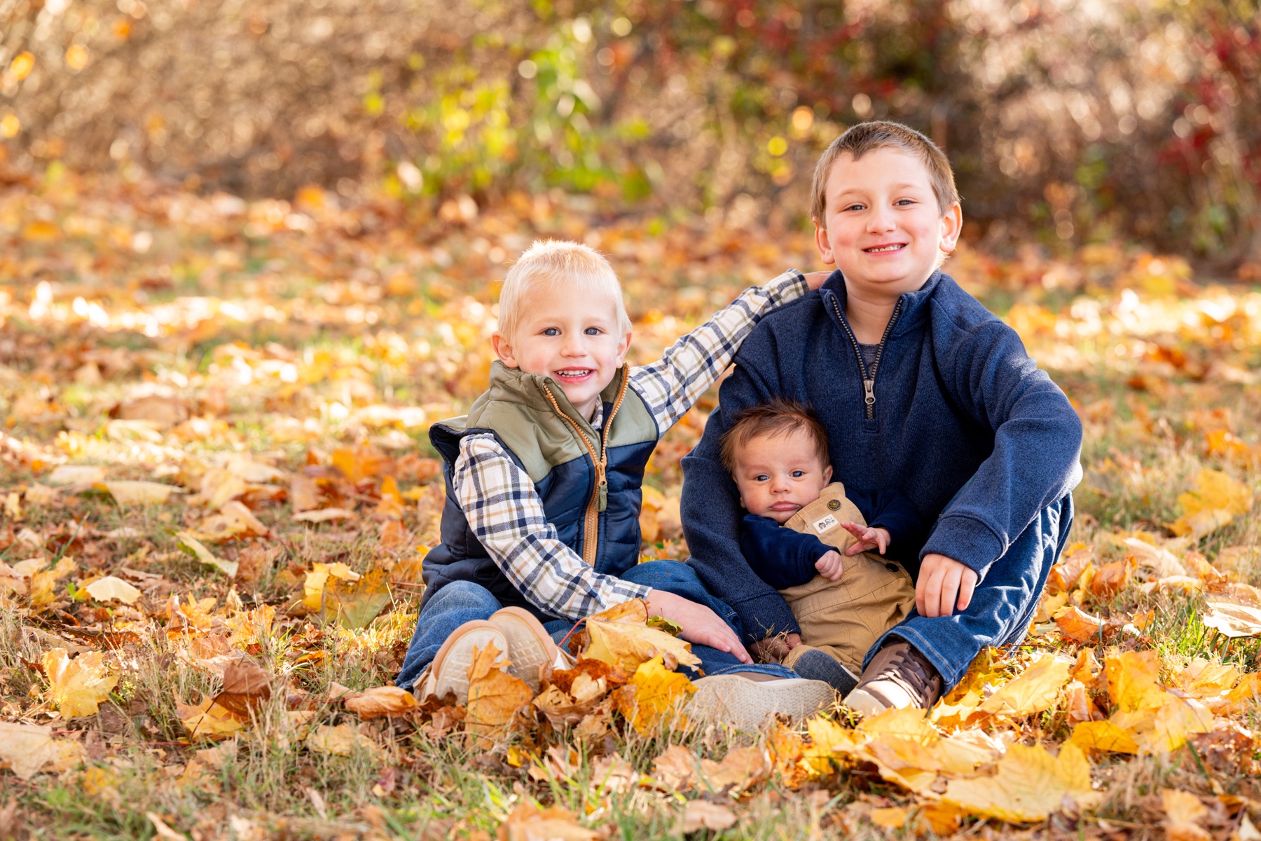 three young boys playing with orange leaves together