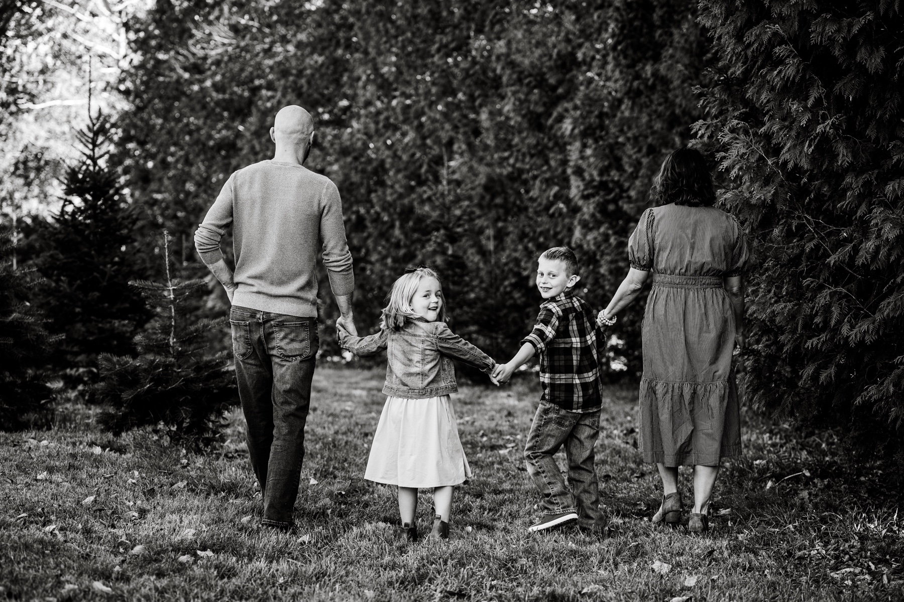 family of four walking through a field holding hands 