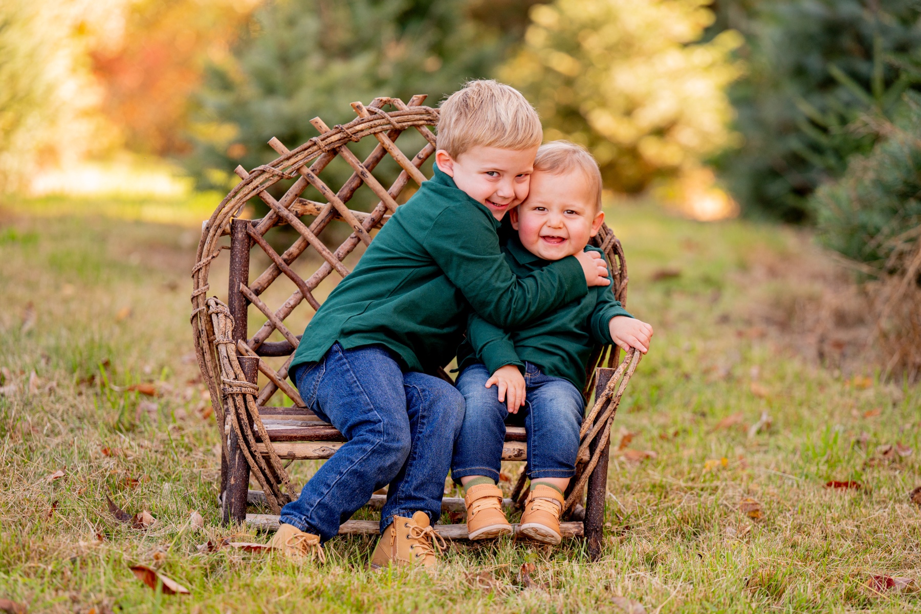 two young boys wearing green shirts and jeans sitting on wooden chair 
