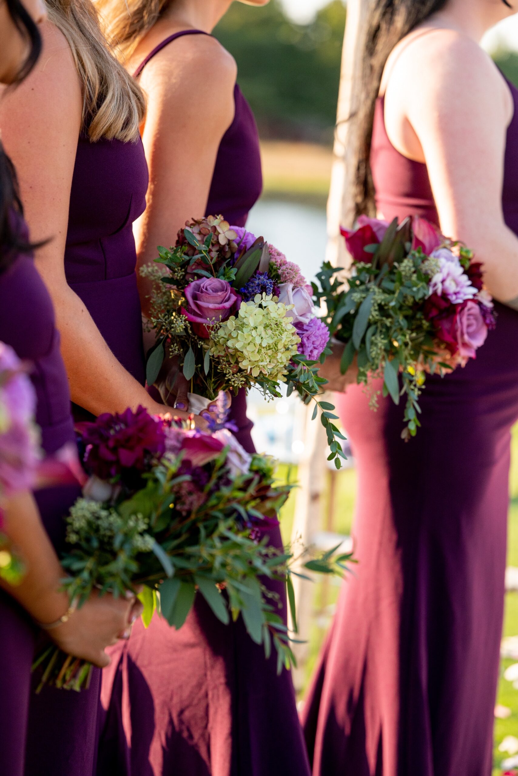 bridesmaids holding purple and green floral bouquets during wedding ceremony
