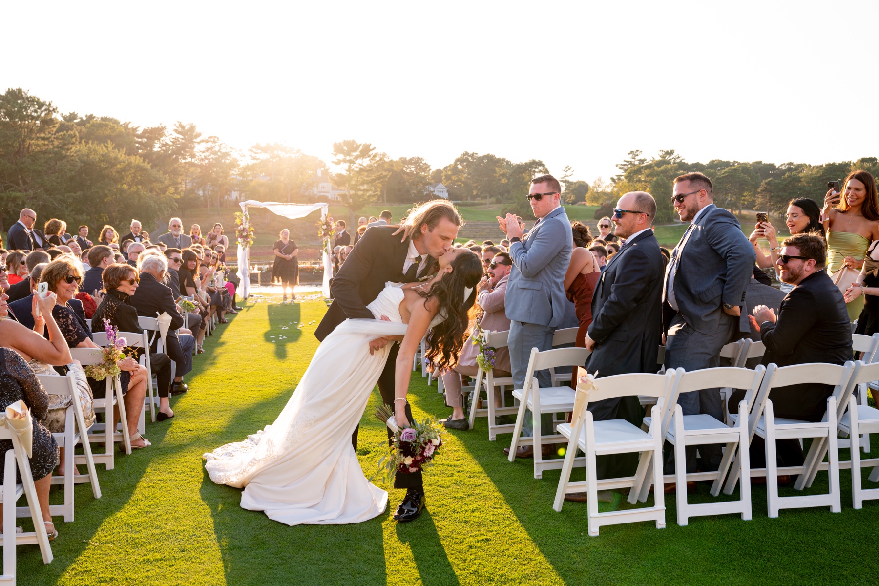 bride and groom kissing at the end of the aisle after their wedding ceremony at Willowbend 