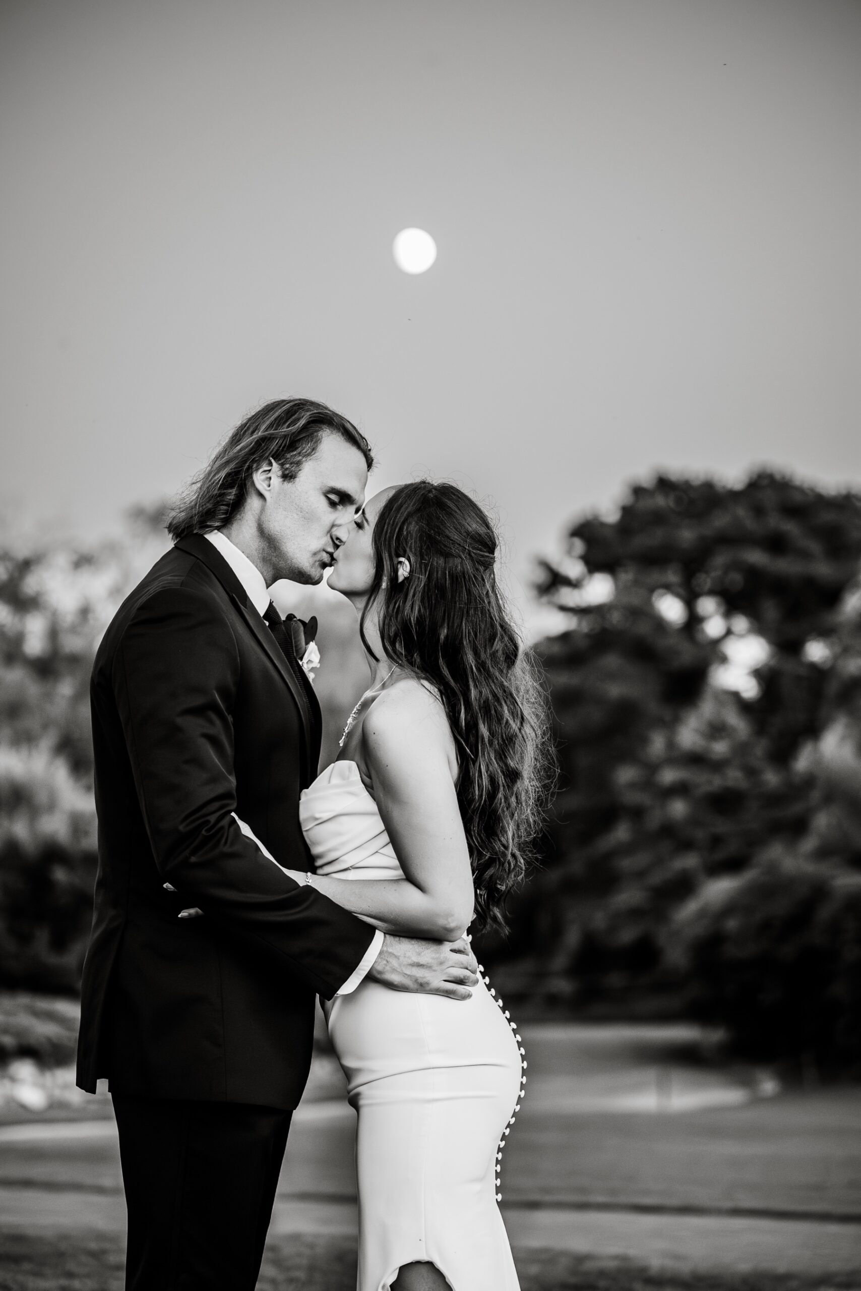 bride & groom kissing with a full moon in the sky