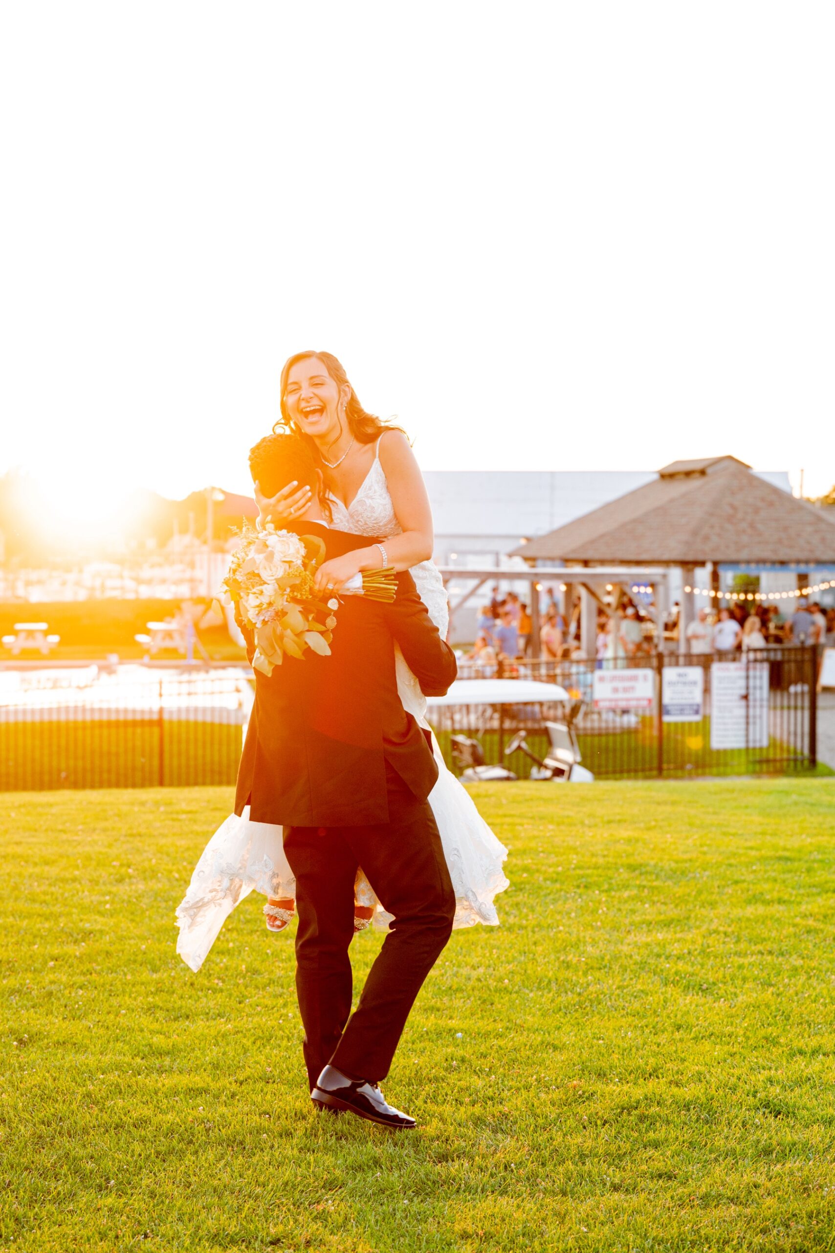 groom carrying bride as she laughs during wedding reception
