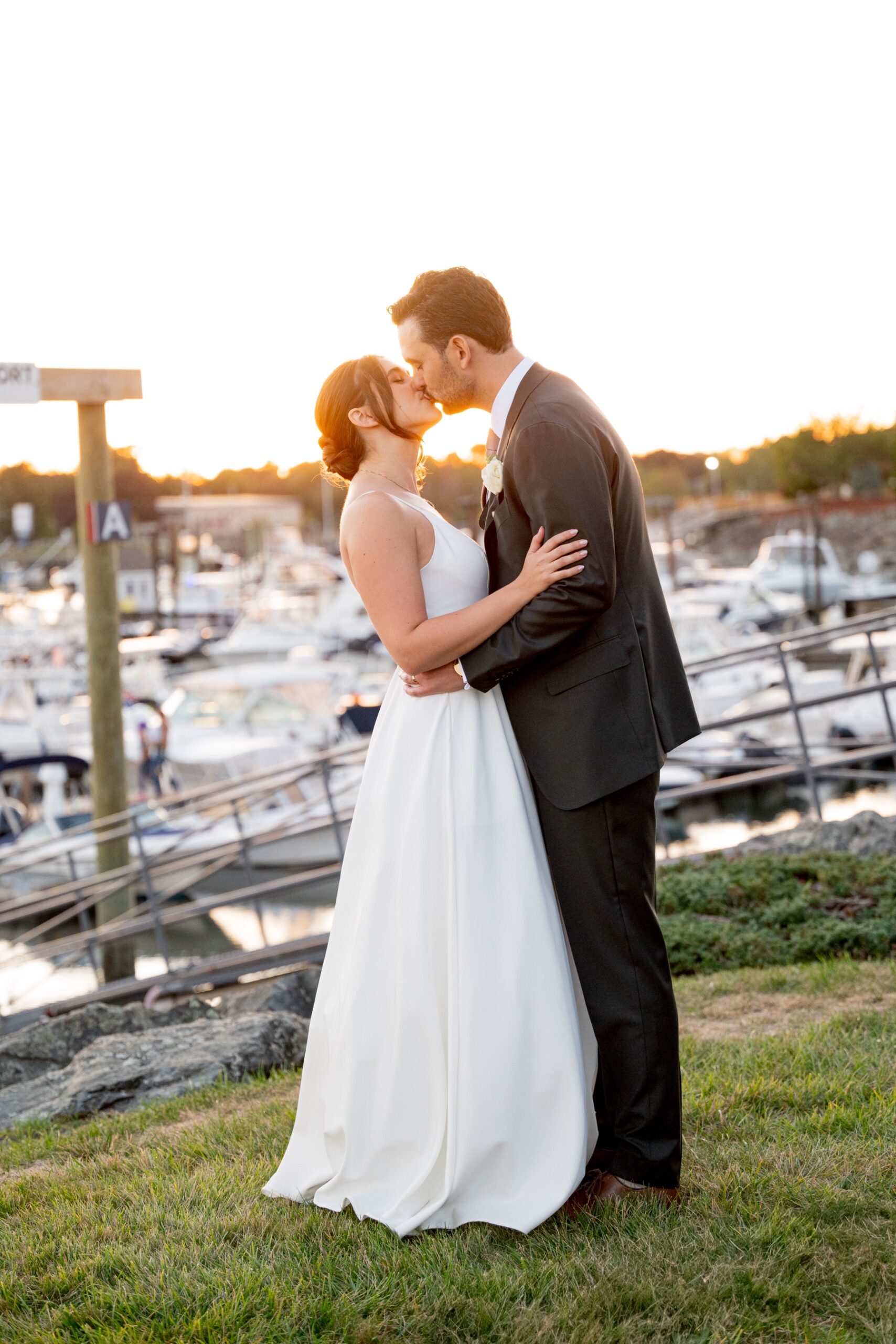 bride and groom kissing with the sunset harbor behind them 