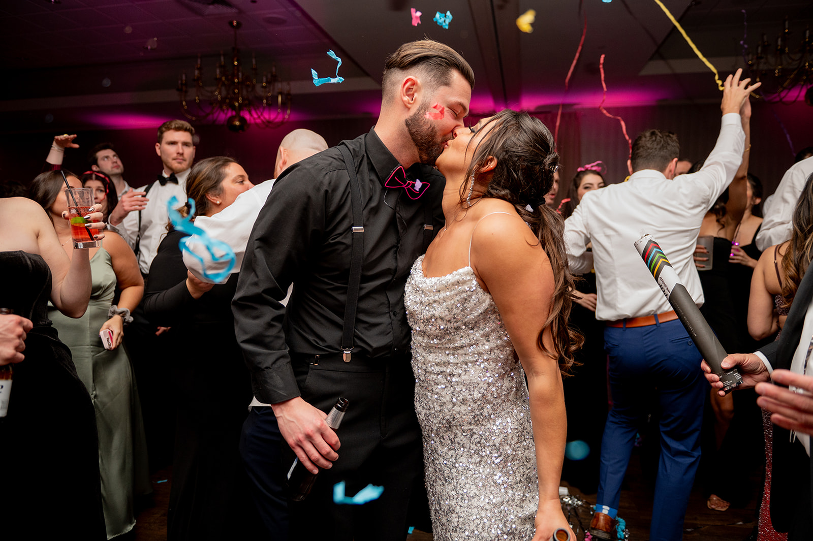 bride & groom kissing during wedding reception with confetti floating around them
