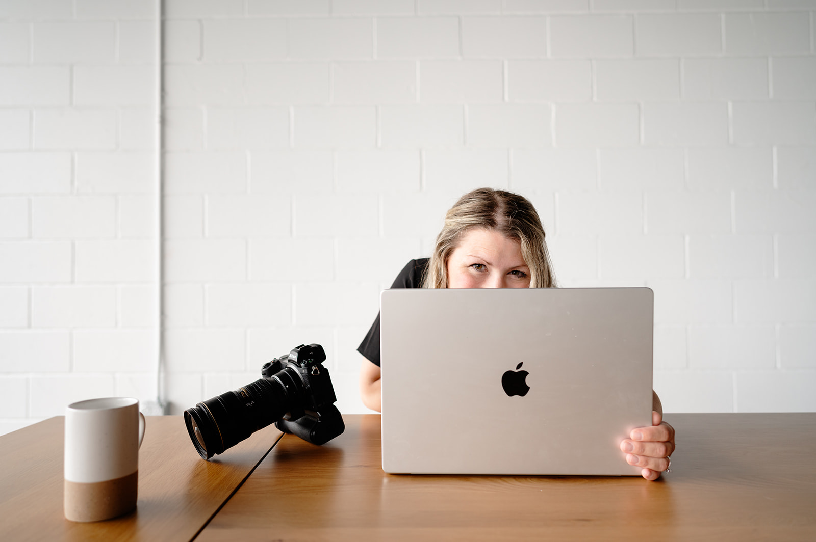 Ali sitting in front of laptop with camera next to her