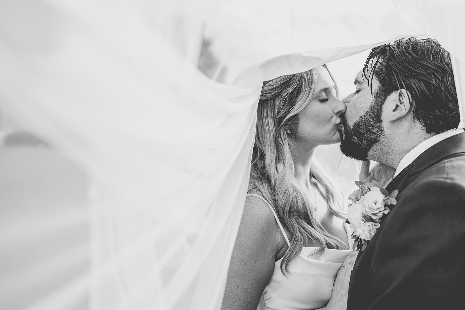 Best wedding veil for photos - Black and white photo of couple kissing under veil