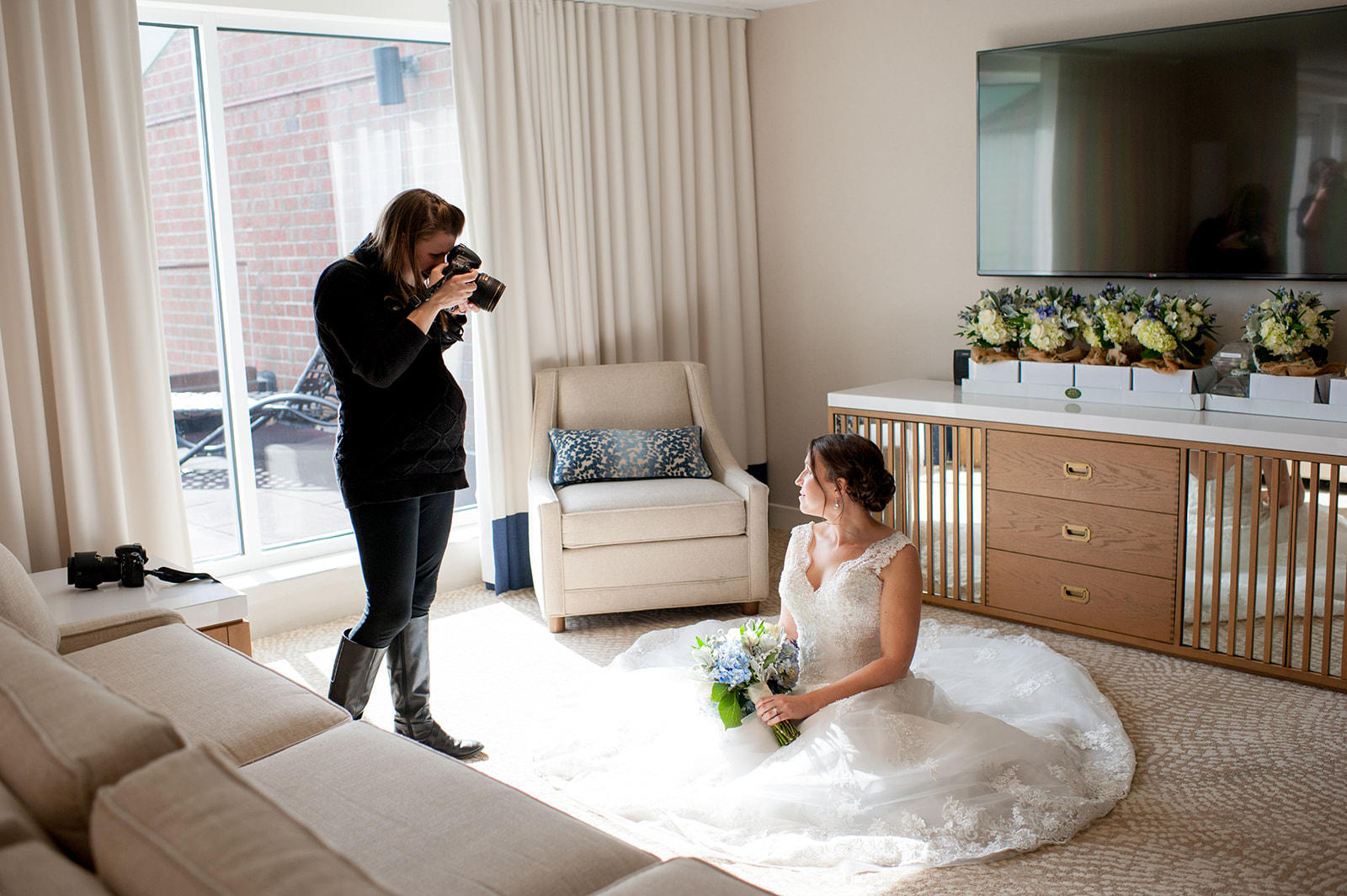 A wedding photographer taking photos of the bride wearing her dress in the bridal suite