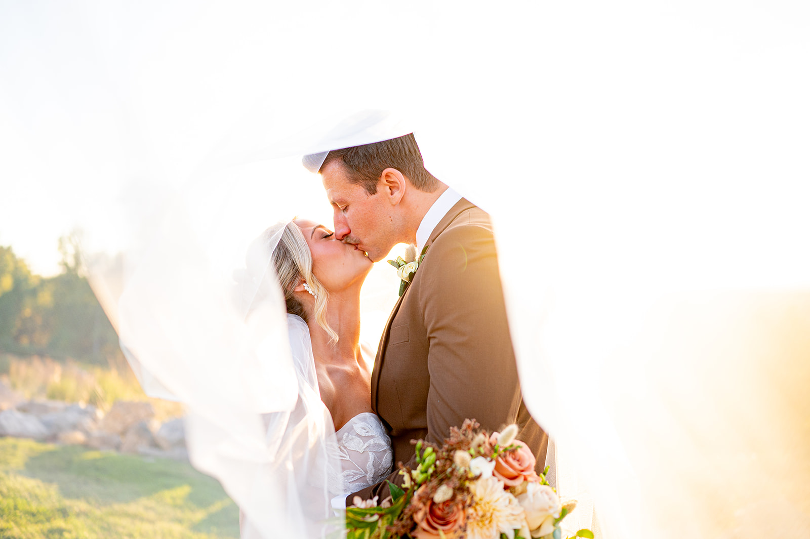Couple kissing under veil backlit with sunlight