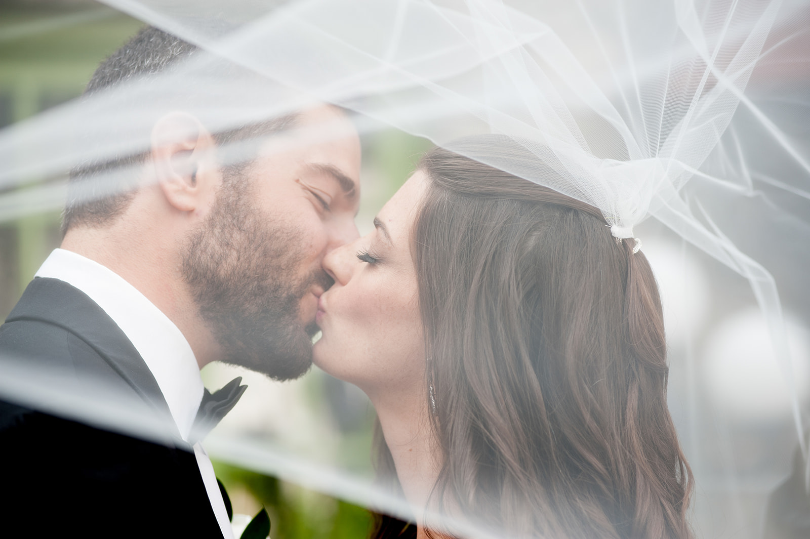 bride and groom kissing under veil that is fully covering them