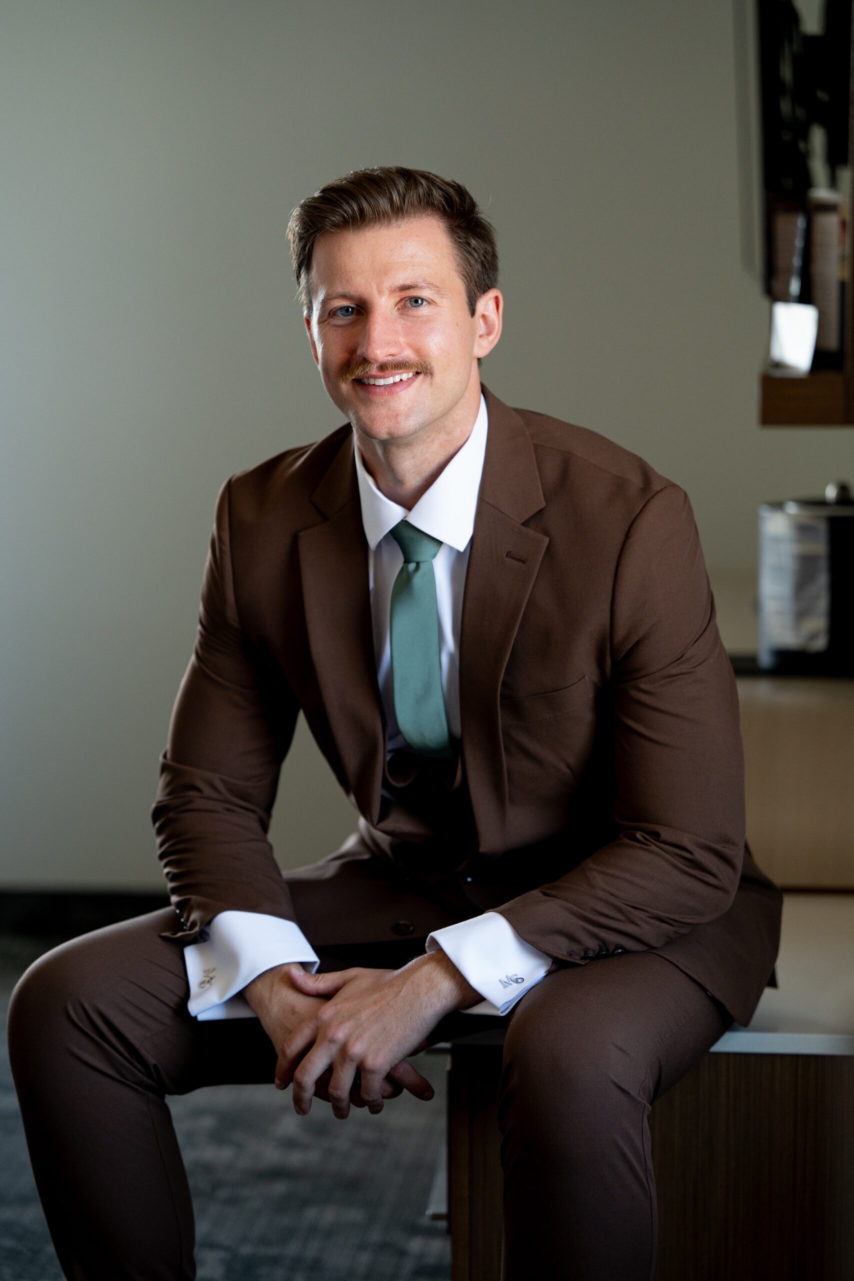 Groom dressed and seated on edge of bed
